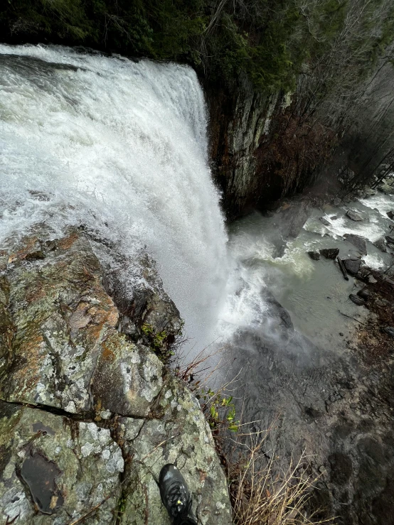 a waterfall running down into the ground next to a rock wall