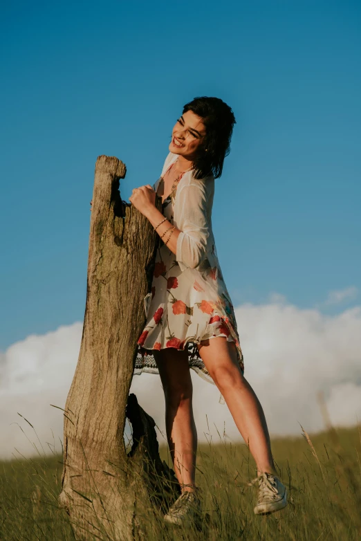 girl poses with her legs on a tree in a field