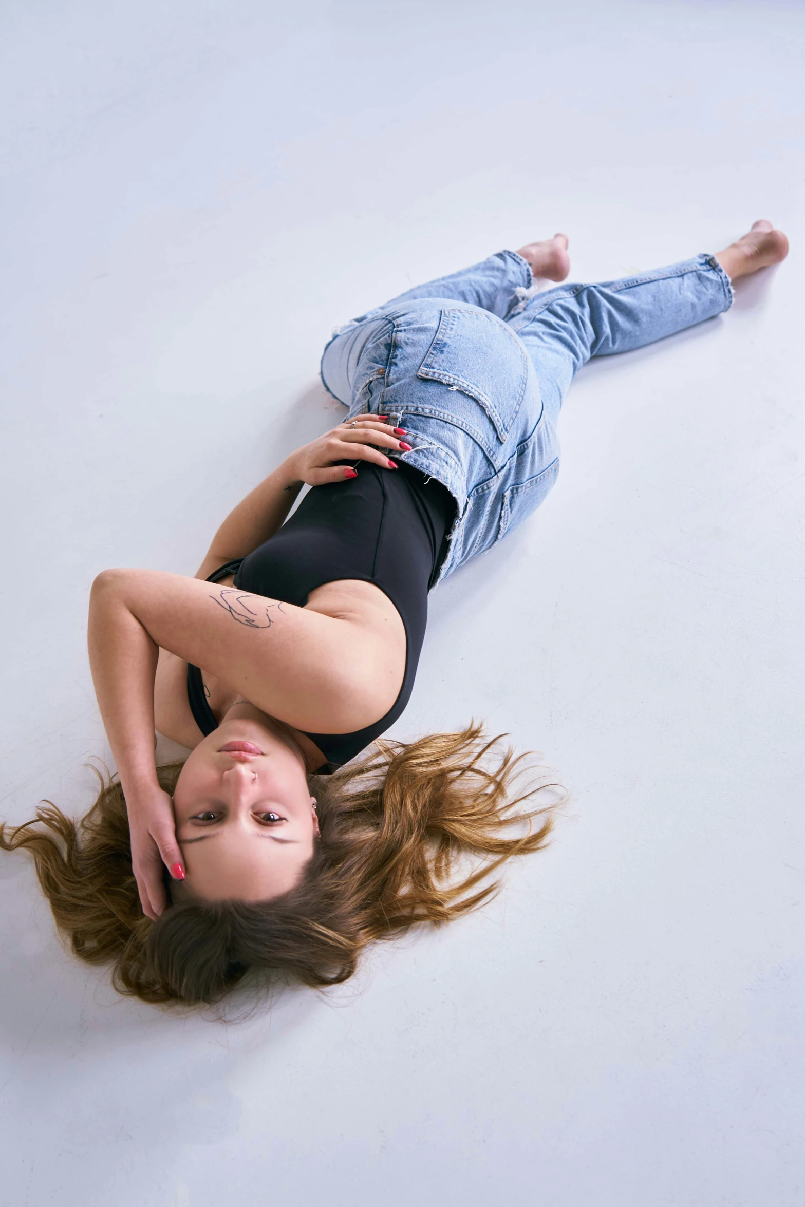 a woman wearing blue denim jacket and jeans top upside down in white studio floor