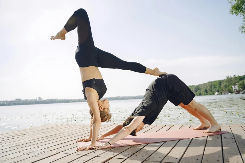 two women doing a yoga poses on a deck by the lake