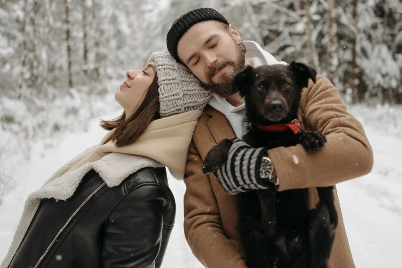 man hugging dog while woman stands by her side