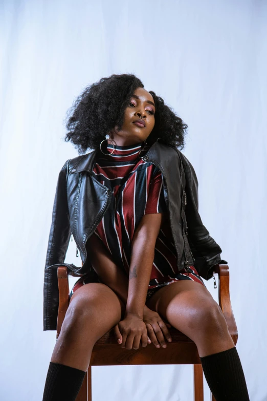 a beautiful black woman sitting on a chair with her legs crossed