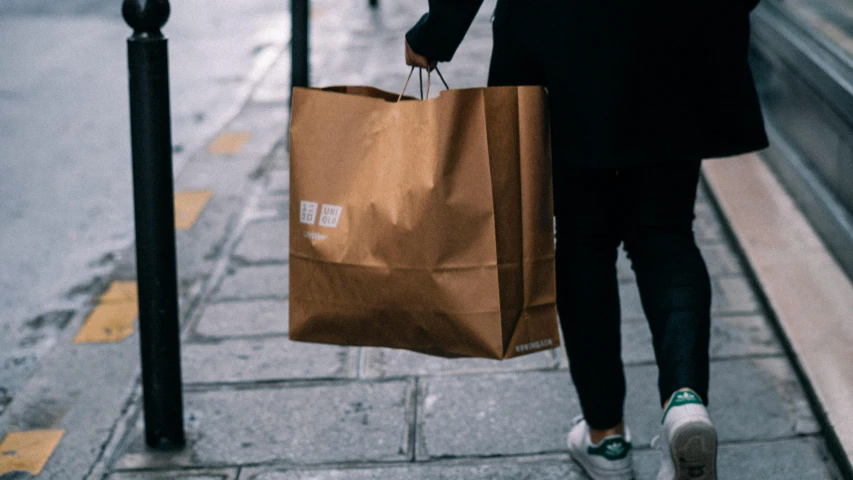 a woman in a jacket carries her shopping bag down the street