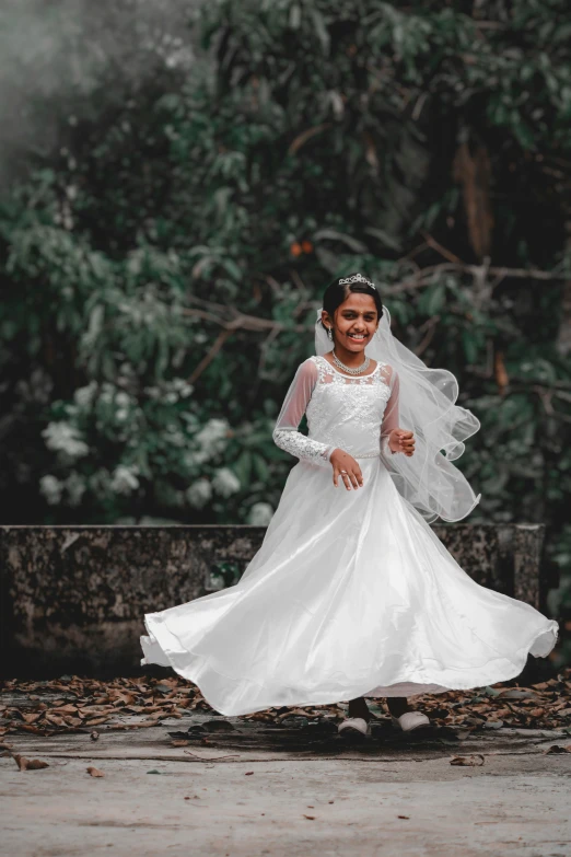 bride in white gown with veil and train standing on cement walkway