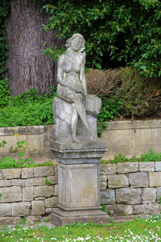 a statue in the middle of a garden by some flowers