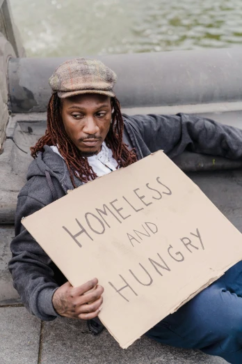 a homeless man holding a sign in his hands