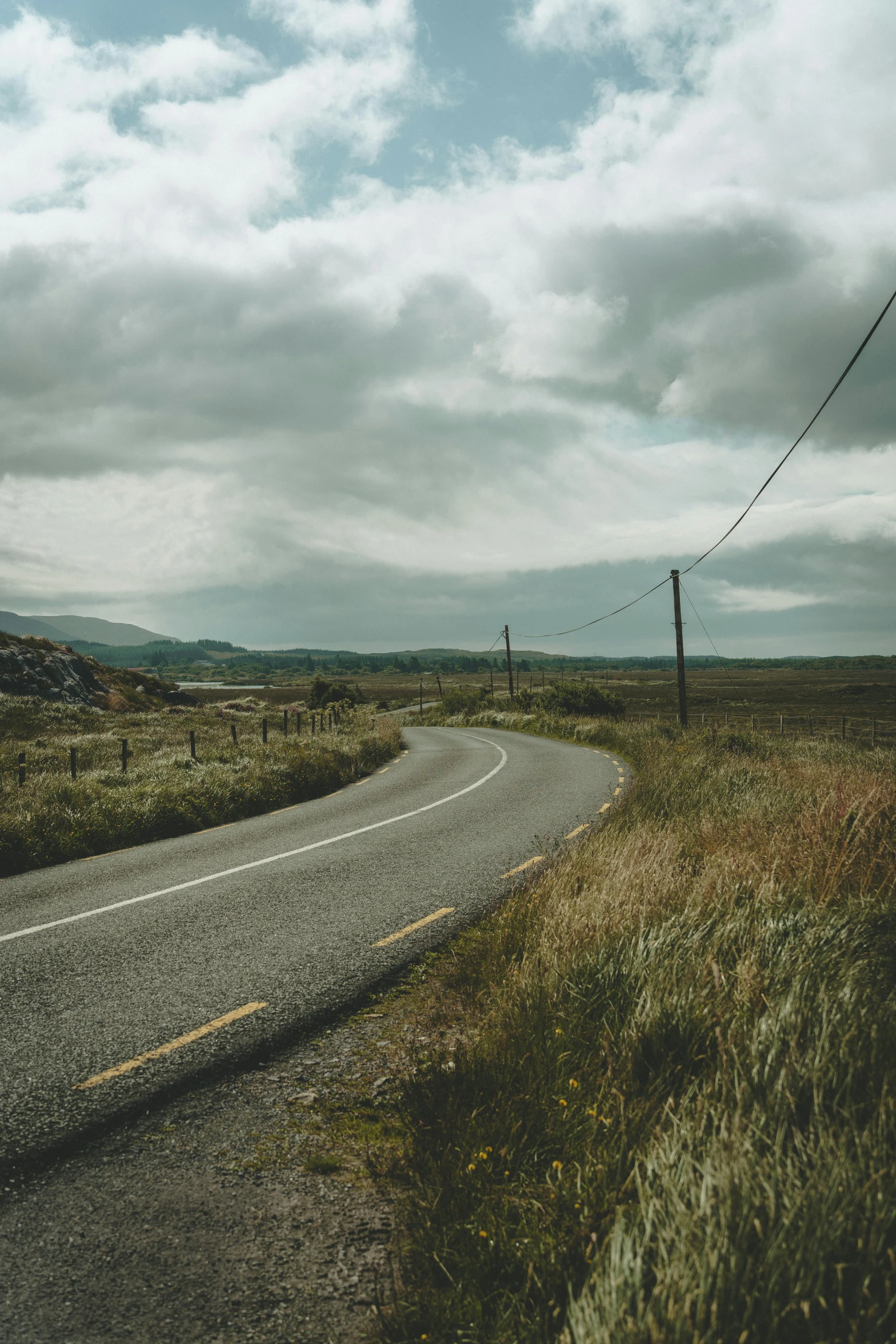 an empty road sits near some wires under cloudy skies