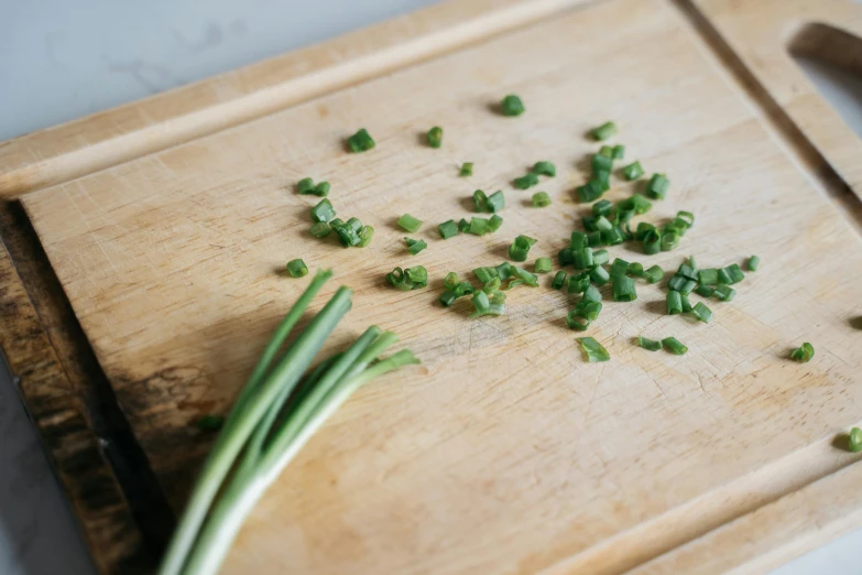 green onions are chopped up and sitting on a  board