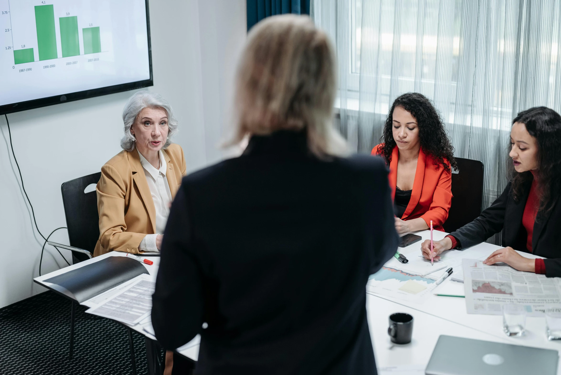 three women are talking while in a meeting room