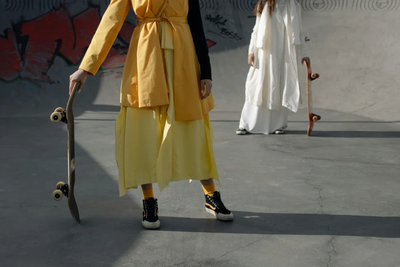 a man in a yellow kimono standing with a skateboard