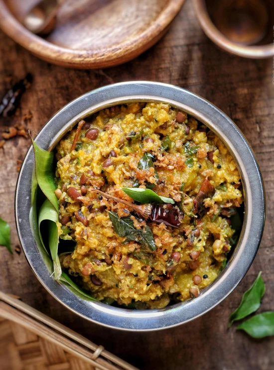 there is a metal bowl filled with food on the table