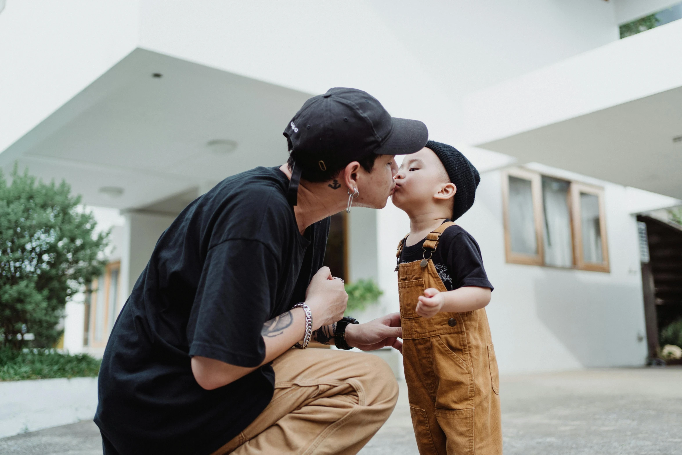 a man kneeling down with a child kissing him