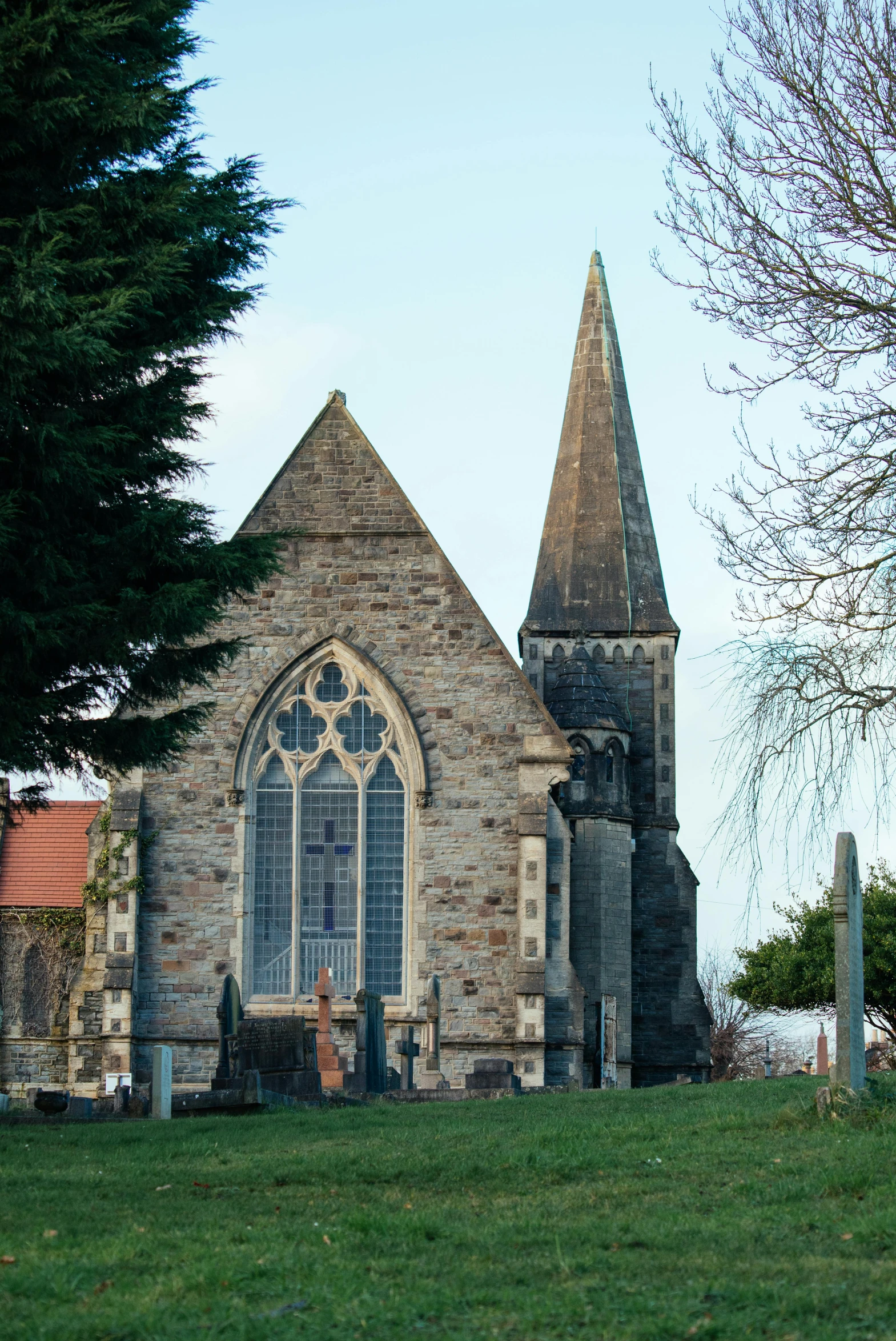 a small church with a tall steeple and trees