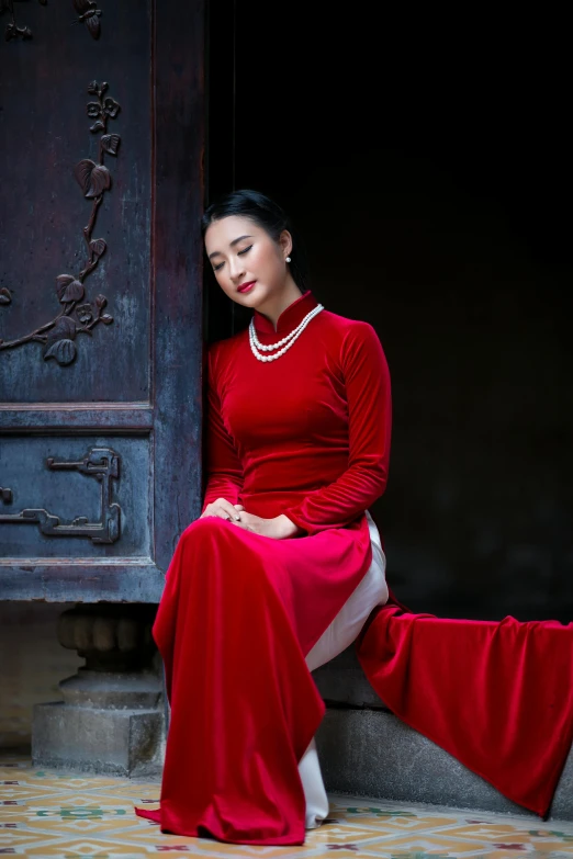 a woman in a red dress sitting on a doorway