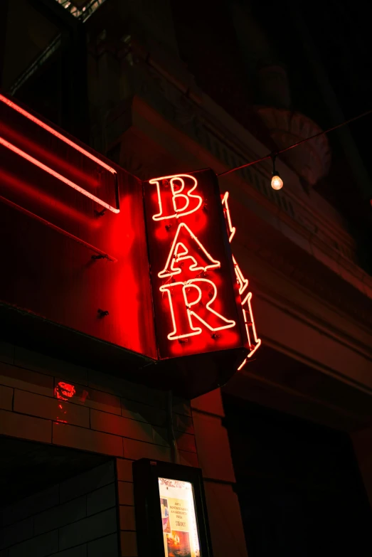 a neon bar sign is glowing red above a building