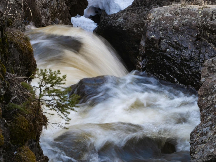 a stream running between rocks covered with snow