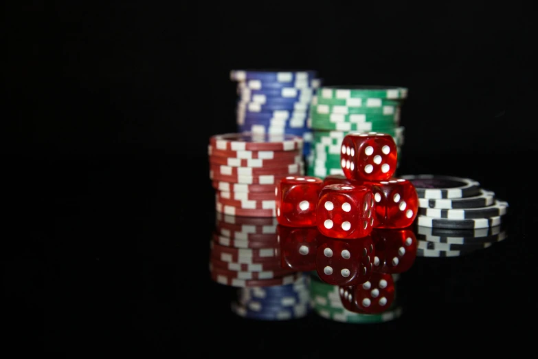 three dices in front of several stacks of poker chips