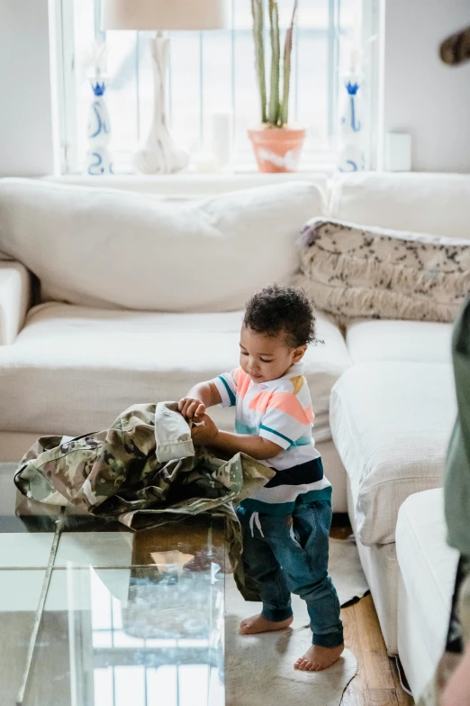 a small child in a living room playing with a piece of luggage