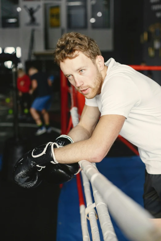 a man in a boxing ring leaning up against the ropes