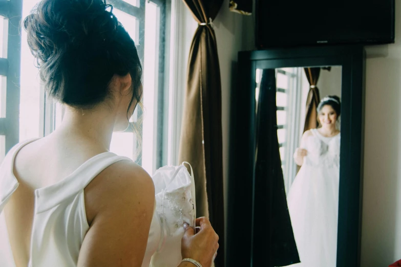 a bride looks at her dress in the mirror