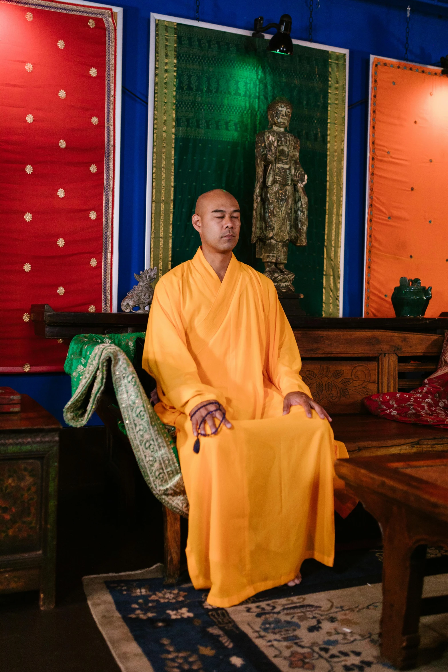 a man in a yellow robe is sitting near colorful tapes