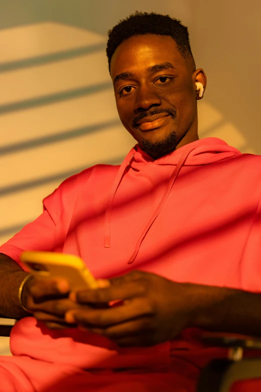 an african american man sitting in front of a white wall