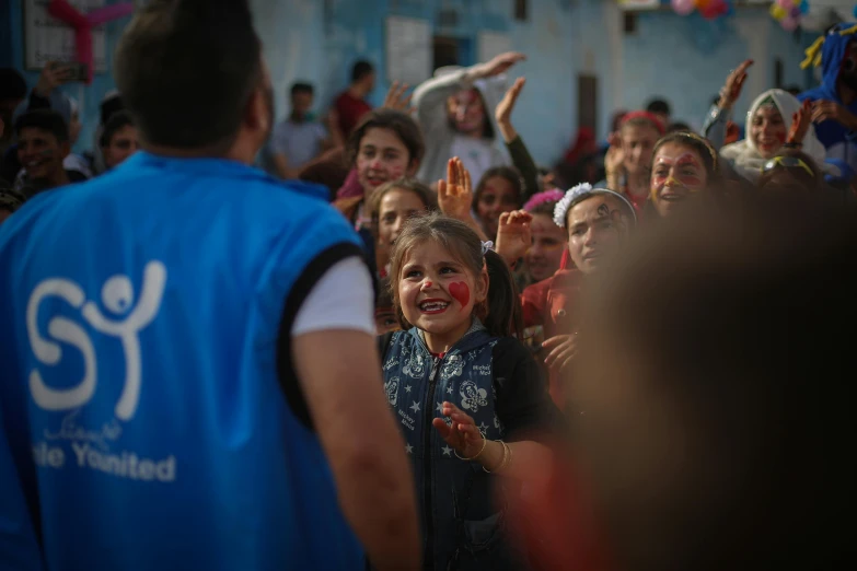 a crowd of children is standing and waving