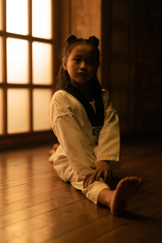 a small girl is sitting on the floor by an open window