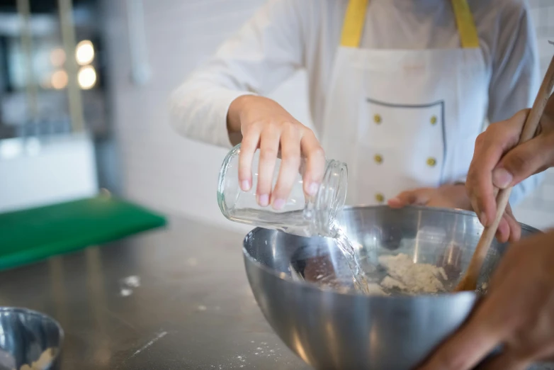 a person pouring water into a bowl in a kitchen