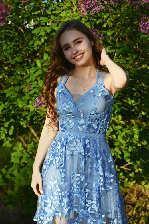 girl with a blue dress posing in front of purple flowers