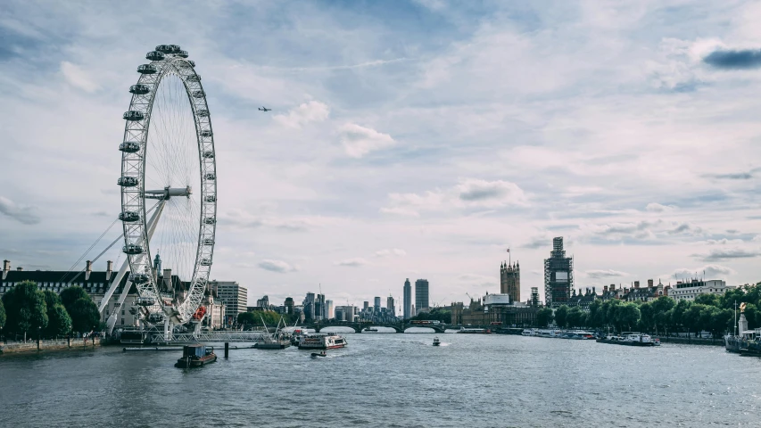 a large ferris wheel on top of a river next to a city