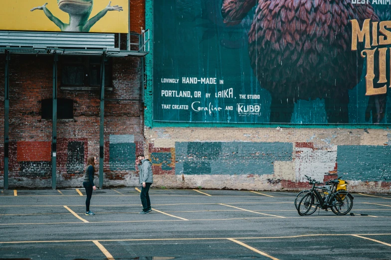 people walking across a parking lot in front of a movie poster