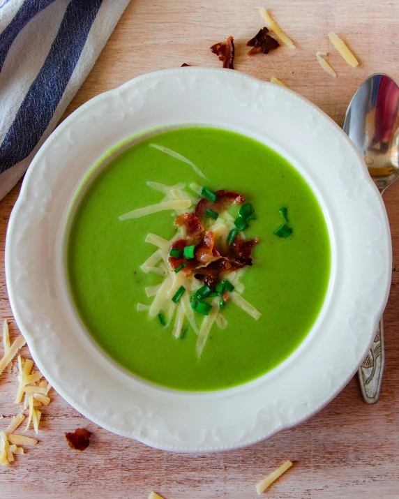 a bowl filled with green pea soup, topped with bacon