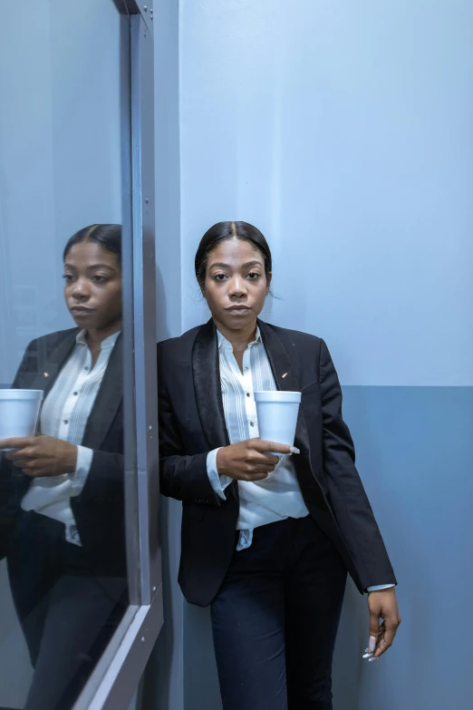 woman in suit standing in an office holding a cup