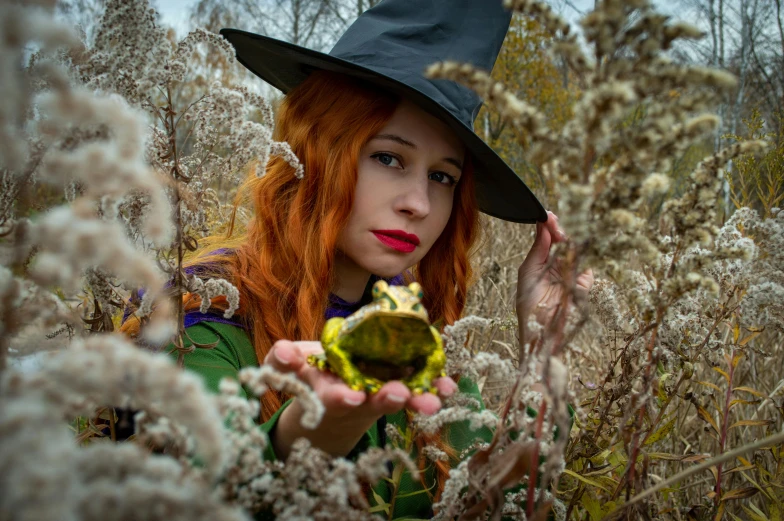 red headed woman in green is holding a fake frog toy