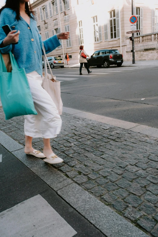 a woman walking across a street carrying a shopping bag