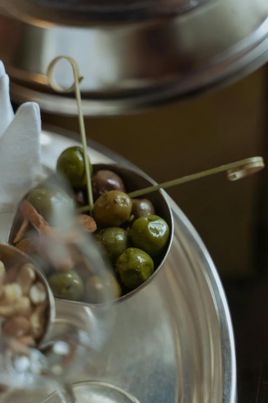 a silver plate filled with green olives and almonds