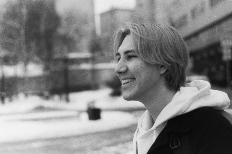 a young man standing next to a brick sidewalk in front of a street