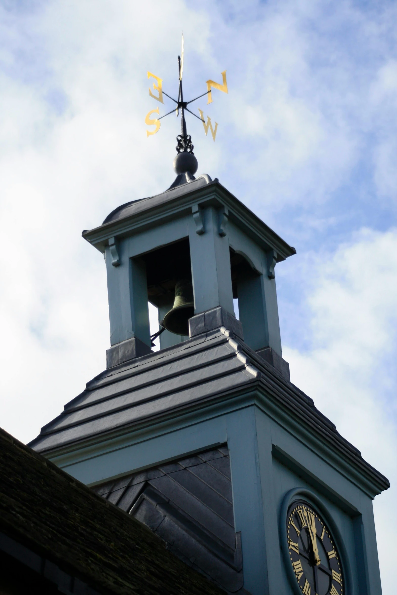 the top of a tower has a clock and weather vane on it