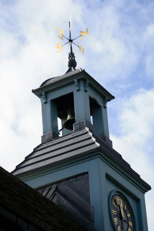 the top of a tower has a clock and weather vane on it