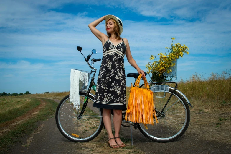 a woman in black dress next to bike and basket