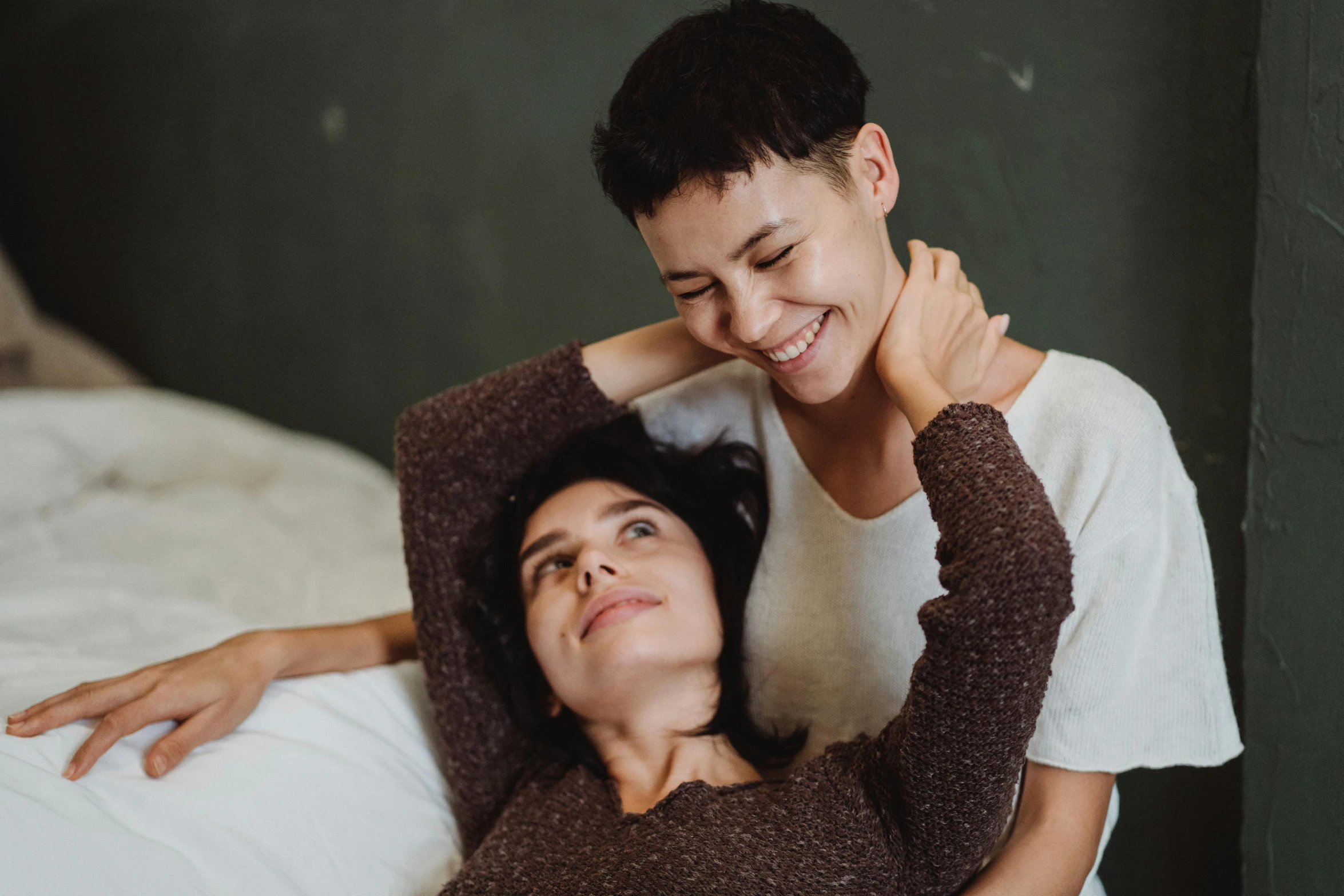 a woman is hugging the neck of another woman on a bed