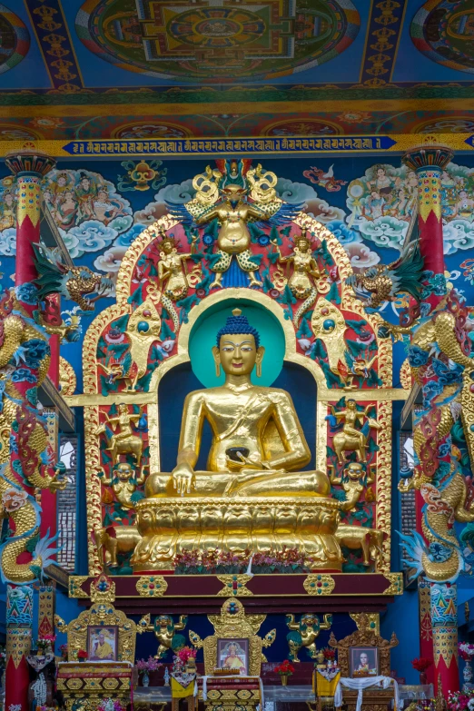 a golden buddha sitting in front of colorful paintings