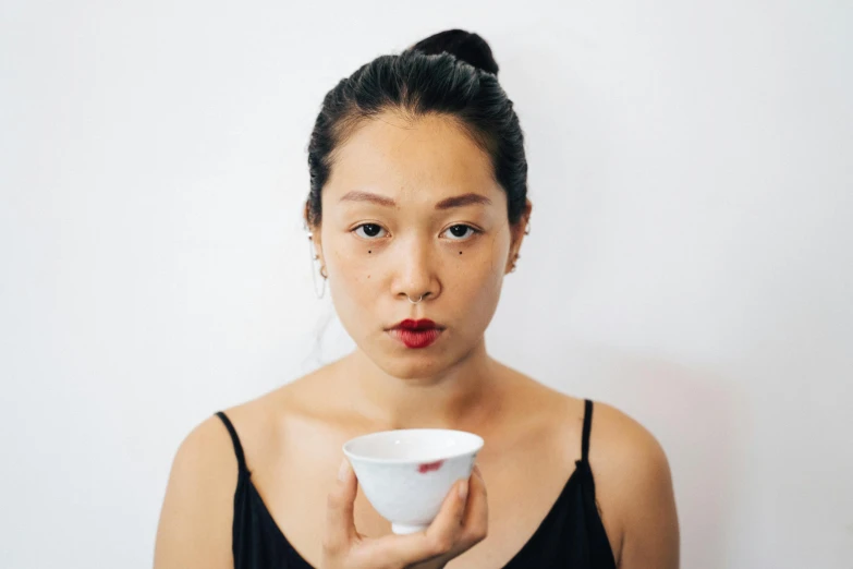 an asian woman is holding a bowl and a cup