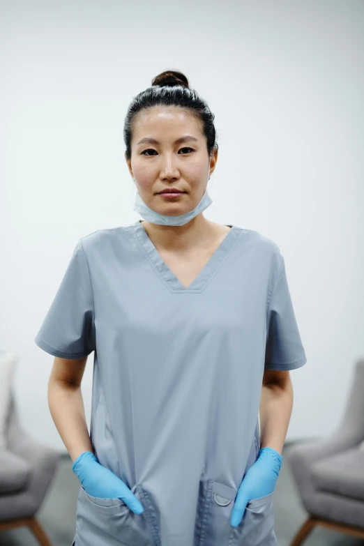 a woman with blue rubber gloves standing in front of a white wall