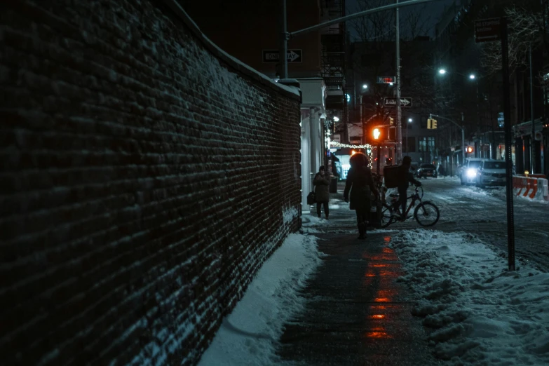 an alley at night with people, bicycles and snow