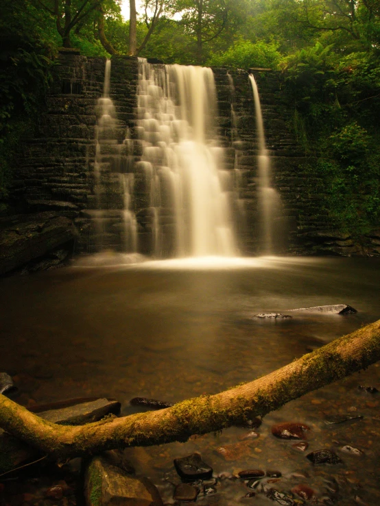 a very tall waterfall surrounded by lush green trees