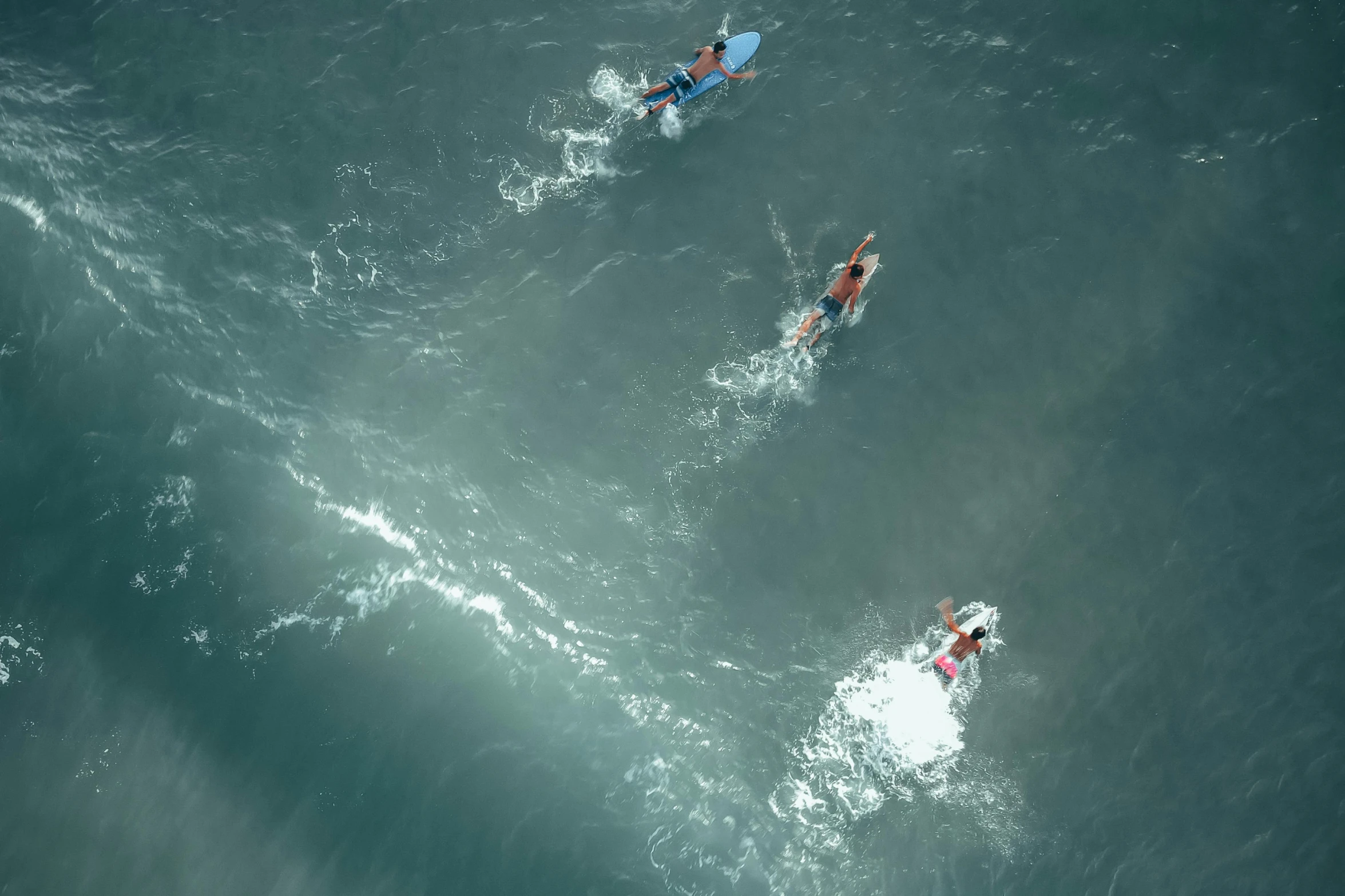 two surfers are riding boards into a wave