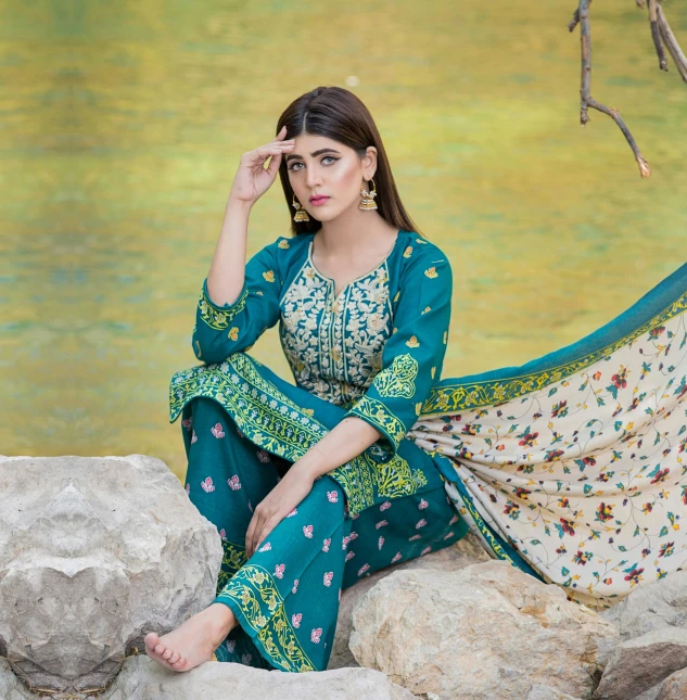 a woman sitting on some rocks in front of a body of water