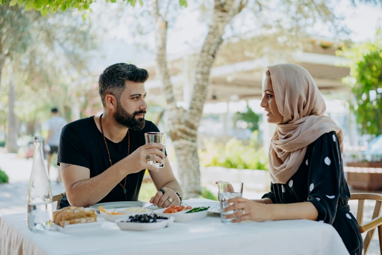 man and woman sit at a table and eat food,